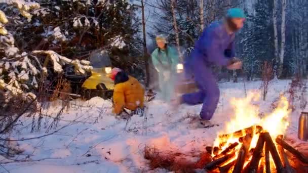 Vinter skog. En ung familj spelar snöbollar i skogen vid elden. Ha kul. — Stockvideo