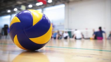 Engelliler için spor. Katta oturan ve ısınma insanlar. Voleybol topu ön planda. Orta atış