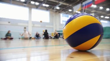 Engelliler için spor. Katta oturan ve oynayan insanlar. Ön voleybol topu