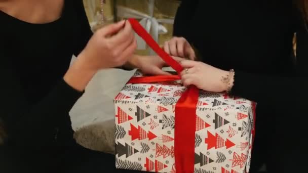 Twee jonge vrouwen ontkoppelen het lint op de grote doos met een cadeau. Handen. — Stockvideo