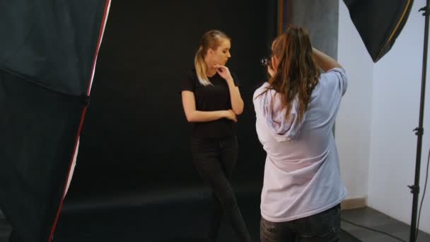 Ung kvinna modeller att ha en fotosession i studion. Ta snaps. Skytte backstage — Stockvideo