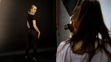 Genç kadın modelinde bir fotoğraf oturumu stüdyoda. Siyah arka plan üzerine siyah giysili model enstantane alarak