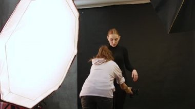 Genç kadın modelinde bir fotoğraf oturumu stüdyoda. Bir fotoğrafçı modelleri elbise sabitleme