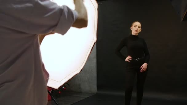 Mujer joven modelo teniendo una sesión de fotos en el estudio. La modelo posa para el fotógrafo — Vídeos de Stock