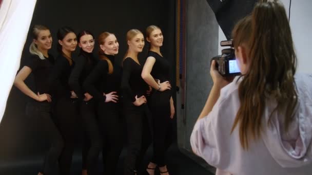 Stüdyoda fotoğraf çekimi olan genç kadın modelleri. Altı farklı türleri birbirlerine tarafından ayakta ve kameraya gülümseyen siyah elbise modelleri — Stok video