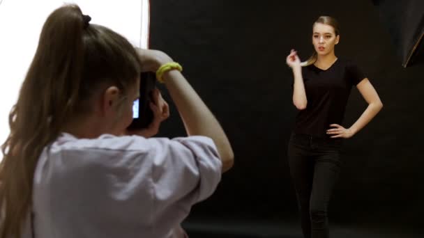 RUSIA, KAZAN. 14-12-2018: Mujer joven modelo teniendo una sesión de fotos en el estudio. Disparando a la modelo con ropa negra. El modelo plantea de manera diferente — Vídeos de Stock