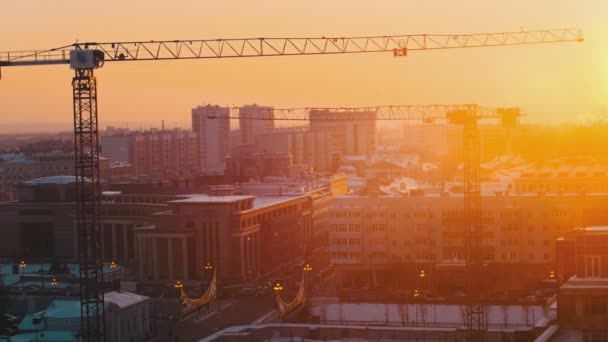 Industrial. Un sitio de construcción en el centro de la ciudad. Grúas elevadoras funcionando. Puesta de sol — Vídeo de stock