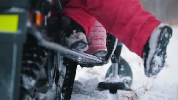 Молодые люди в яркой одежде садятся на снегоход и уезжают — стоковое видео