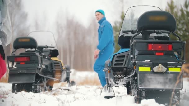 Jóvenes con ropa brillante subiendo a las motos de nieve. Movimiento lento — Vídeo de stock