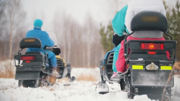 Jóvenes con ropa brillante subiendo a las motos de nieve. Comenzando una carrera de velocidad. Movimiento lento — Vídeo de stock