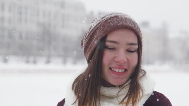 Eine junge lächelnde Frau, die im Winter draußen steht. mit weißem Schal — Stockvideo