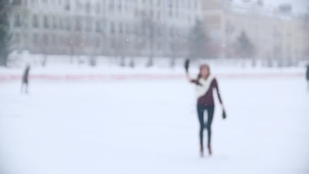 Μια νεαρή γυναίκα παγοδρόμιο έξω. Βλέπει το φίλο του, κουνώντας τους με ένα χέρι, skate, πιο κοντά στην κάμερα. Αργή κίνηση — Αρχείο Βίντεο