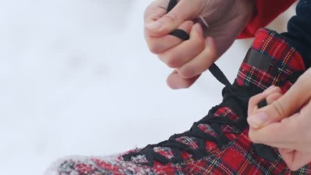 Winter season. A woman sits down and starts to tie her shoelaces on bright red ice skating shoes — Stock Video