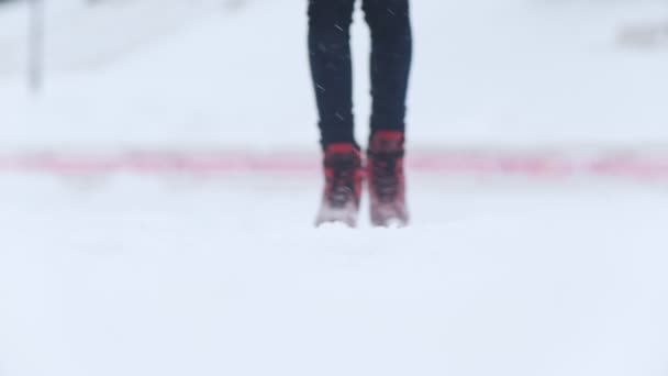 Uma jovem mulher patinando no gelo em patins vermelhos brilhantes lá fora. Movimento lento — Vídeo de Stock