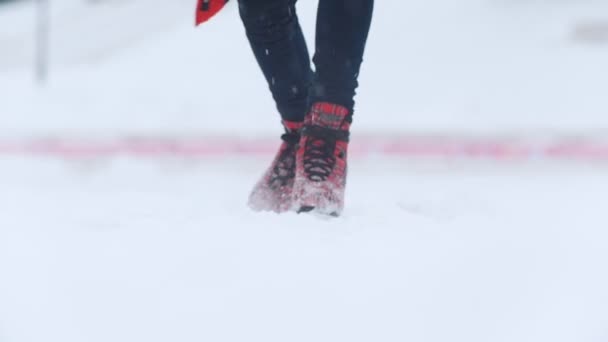 Uma jovem mulher patinando no gelo em patins vermelhos brilhantes lá fora. Uma forte queda de neve. Movimento lento — Vídeo de Stock