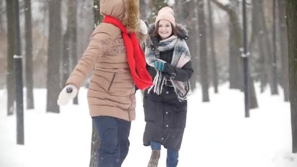 Zwei junge Frauen im winterlichen Park, die zusammen Fangen spielen und Spaß haben — Stockvideo