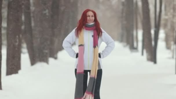 Winterpark. Eine Frau mit leuchtend roten Haaren steht auf dem Bürgersteig. Springen — Stockvideo