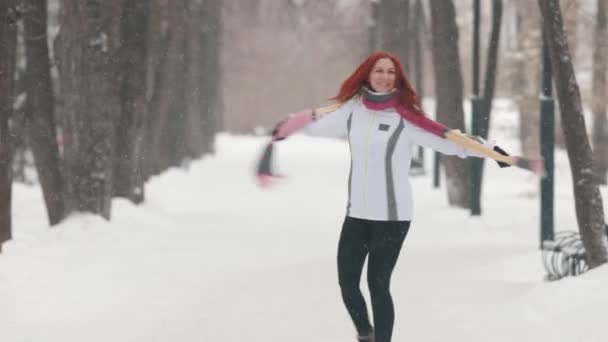 Зимовий парк. Щаслива жінка з яскраво-червоним волоссям кружляє навколо і посміхається — стокове відео