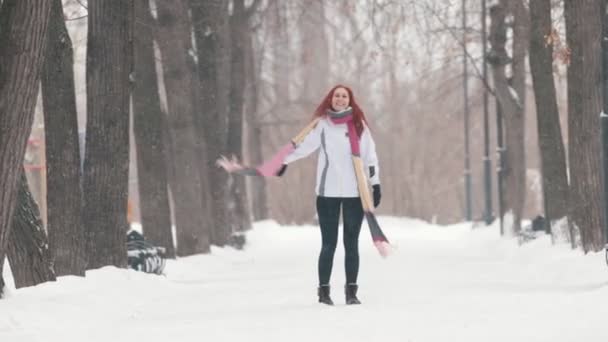 Winter park. Een vrouw met fel rood haar staande op de stoep. Doen van activiteiten — Stockvideo