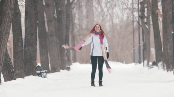 Parque de invierno. Una mujer de pelo rojo brillante de pie en la acera. Haciendo actividades — Vídeos de Stock