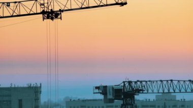 Endüstriyel. Şehrin ortasında bir inşaat alanında. Çalışma vinç kaldırma. Pembe günbatımı