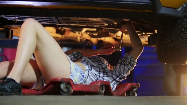 Služba auto. Sexy dívka mechanik ležící pod auto a upravuju. Práce s klíčem — Stock video