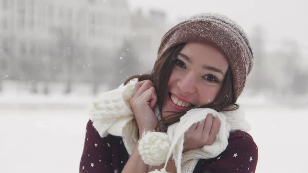 Uma jovem mulher sorrindo de pé no inverno lá fora. Vestindo lenço branco e tocando-o com as mãos — Fotografia de Stock