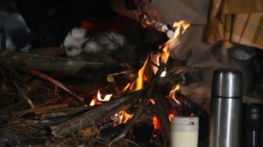 Grup arkadaşıyla birlikte ormanda iyi vakit geçiriyor. Kış ormandaki şenlik ateşi. Gece vakti. Lokum kızartma. Thermocouples karda hazır. Ağır çekim. Yakın çekim