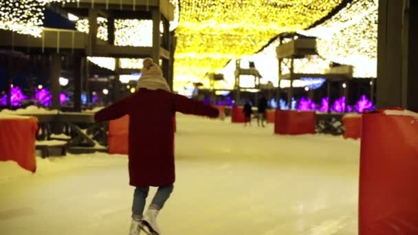 Eine junge Frau und ein junger Mann beim Schlittschuhlaufen auf der Eisbahn. zurück — Stockvideo