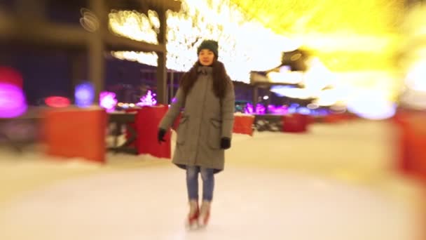Une jeune femme debout sur une patinoire ouverte, souriante et agitant la main — Video