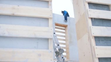 İnşaat alanında. Bina duvar üstünde duran bir adam işçi