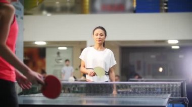 Pin pon oynamaya. Genç kadın başka bir kadınla masa tenisi oynarken