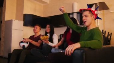 Birlikte vakit arkadaşlar. Kanepede oturan, futbol izlerken ve takım için tezahürat dört gençler