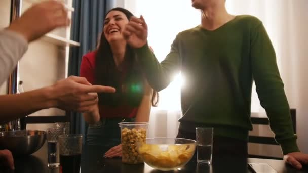 Εταιρεία φίλων νέος ελεύθερος χρόνος που στέκεται μαζί στην κουζίνα. Μια νεαρή γυναίκα γελάει — Αρχείο Βίντεο