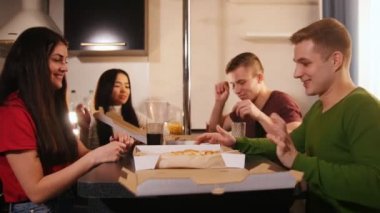 Mutfakta pizza kutusunu açıp bir parça alarak üzerinde dört aç genç arkadaşlar