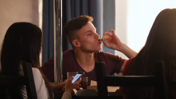 Amigos sentados en la cocina. Joven comiendo pizza — Vídeo de stock