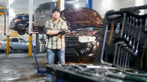 Car-service. Mekaniker man som stod vid bilen hålla ett verktyg och tittar i kameran — Stockvideo