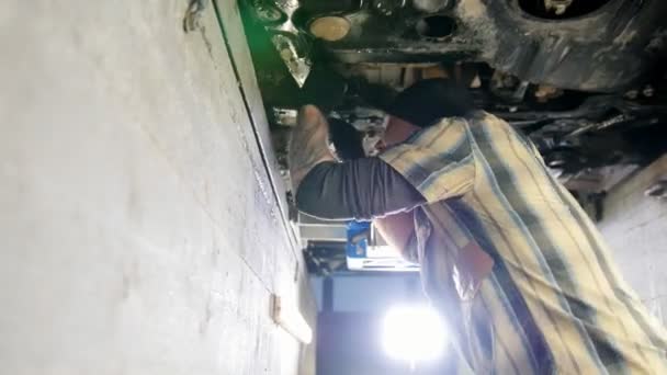 Servicio de coches. Hombre mecánico parado en foso de inspección y trabajando con una herramienta — Vídeos de Stock