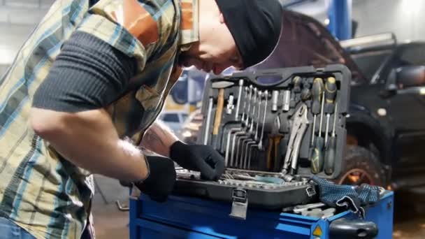 Servicio de coches. Mecánico hombre elegir una herramienta en el caso — Vídeos de Stock