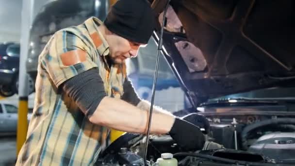 Servizio auto. Uomo meccanico in piedi accanto alla macchina con cappuccio aperto e riparazione auto con una chiave inglese — Video Stock