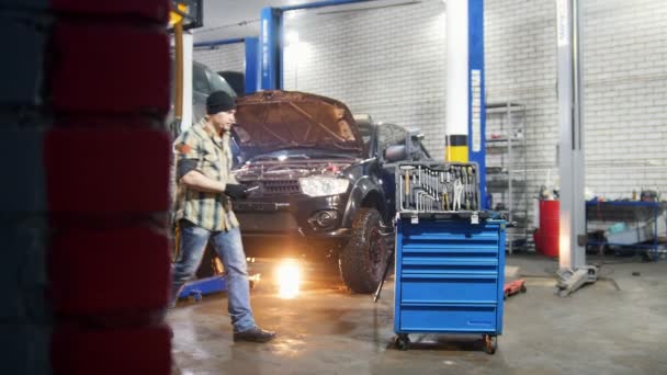 Autoservis. Opravy auto mechanik muž. Přijde ke krytu nástroje změna nástroj a jde zpět do práce — Stock video