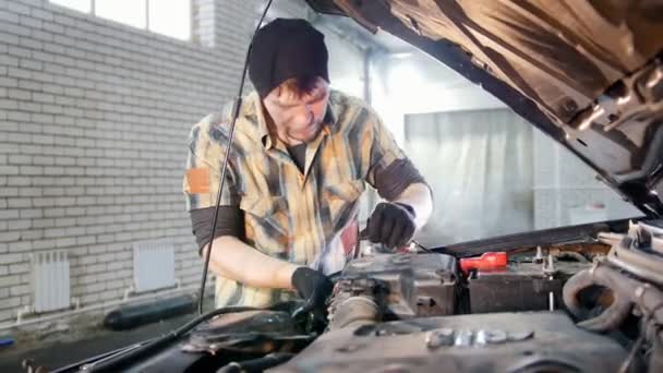 Υπηρεσία αυτοκινήτων. Μηχανικός άνθρωπος βγάζοντας ένα μέρος του αυτοκινήτου κάτω από την κουκούλα — Αρχείο Βίντεο