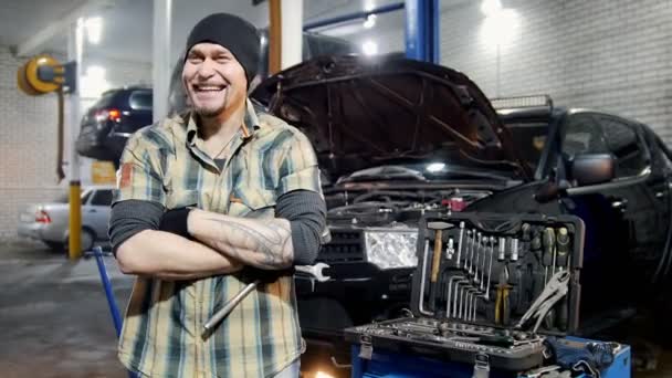 Autoservice. Brutale mechanic man die door de auto en grijnst — Stockvideo