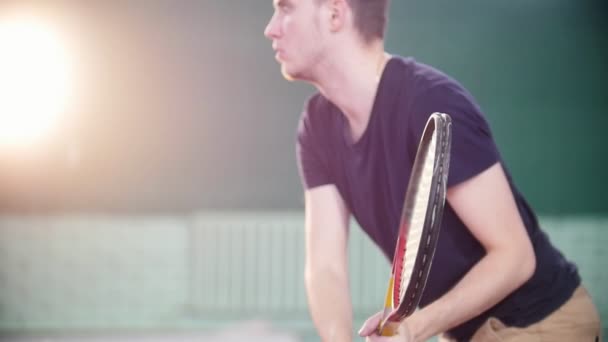 Een jonge man met tennis binnenshuis. Vegen met een raquet — Stockvideo