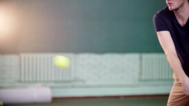 Молодой человек играет в теннис в помещении. Бей по мячу — стоковое видео