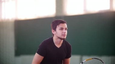 Tenis kortunda eğitim. Genç adam oyun için hazırlanıyor ama tenis topları tarafından dağınık. Kendini bir raquet ile kaplama