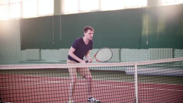 Entrenamiento en la cancha de tenis. Joven preparándose para el juego, pero se dispersa por pelotas de tenis — Vídeo de stock