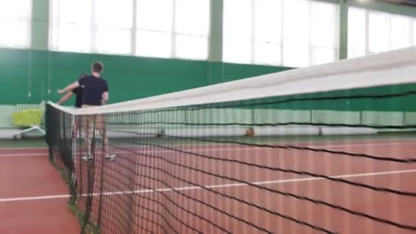 テニスコートでトレーニング 試合前にウォーミング アップの若い男性 フォーカスとカートのグリッドは 背景にテニス ボールでいっぱい ミディアム ショット — ストック動画