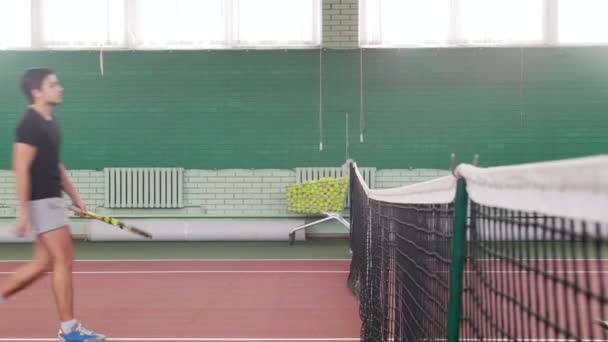 Zwei junge Männer auf dem Tennisplatz. näher ans Gitter kommen und Hände schütteln — Stockvideo
