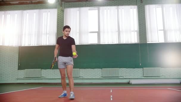 Školení na tenisový kurt. Mladý muž chytit míč od podlahy a směn to — Stock video